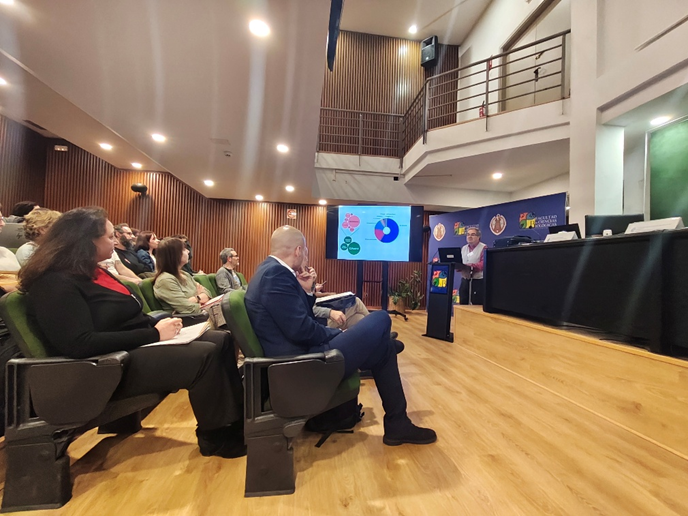 Un momento de la intervención en el salón de actos, donde se proyectan datos sobre la procedencia de los asistentes.